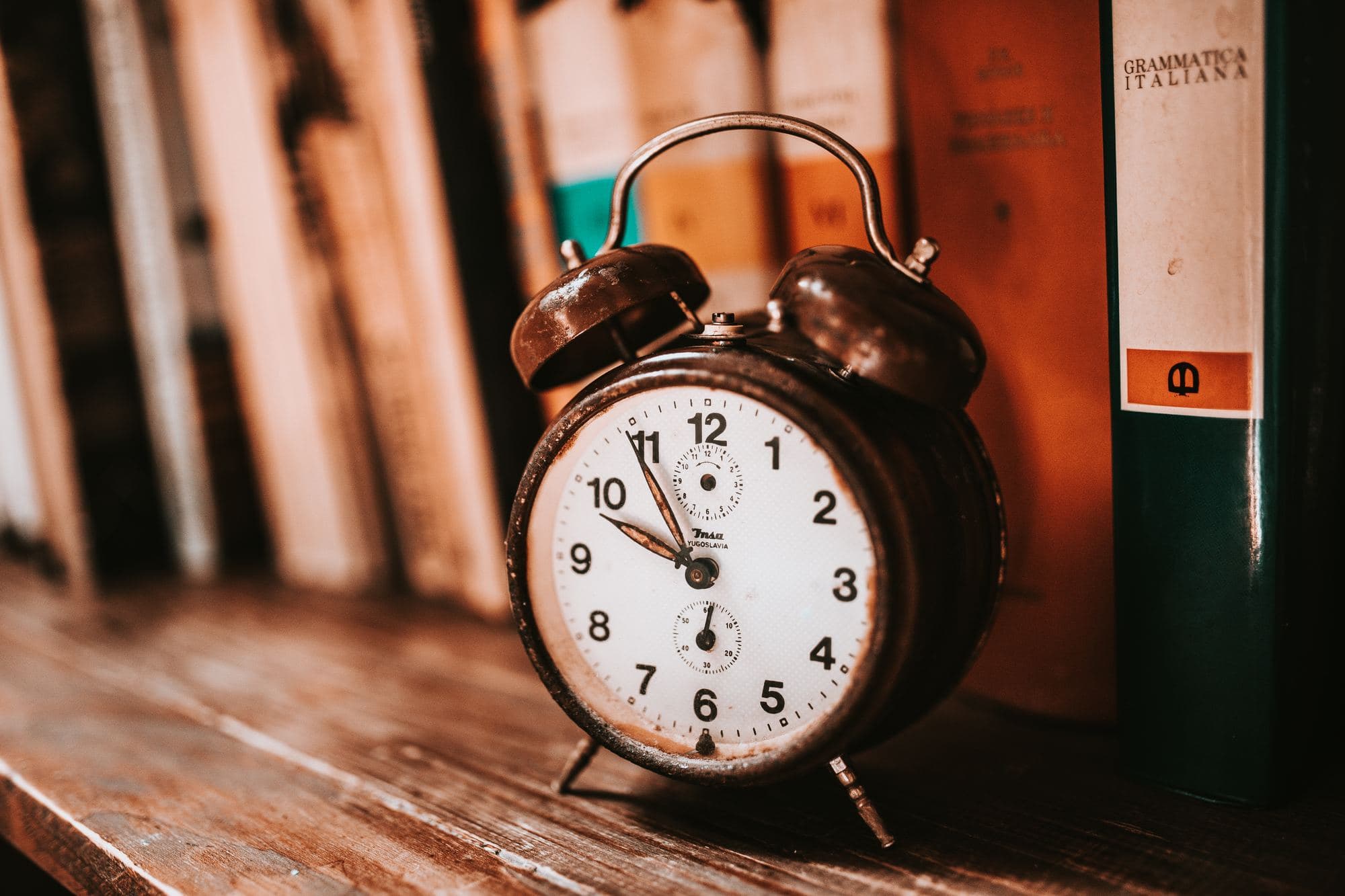 An old alarm clock on a bookshelf