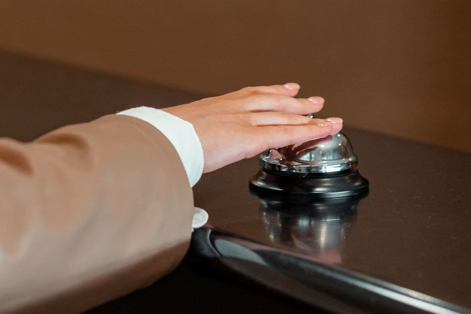 A hand rings the bell on a reception desk