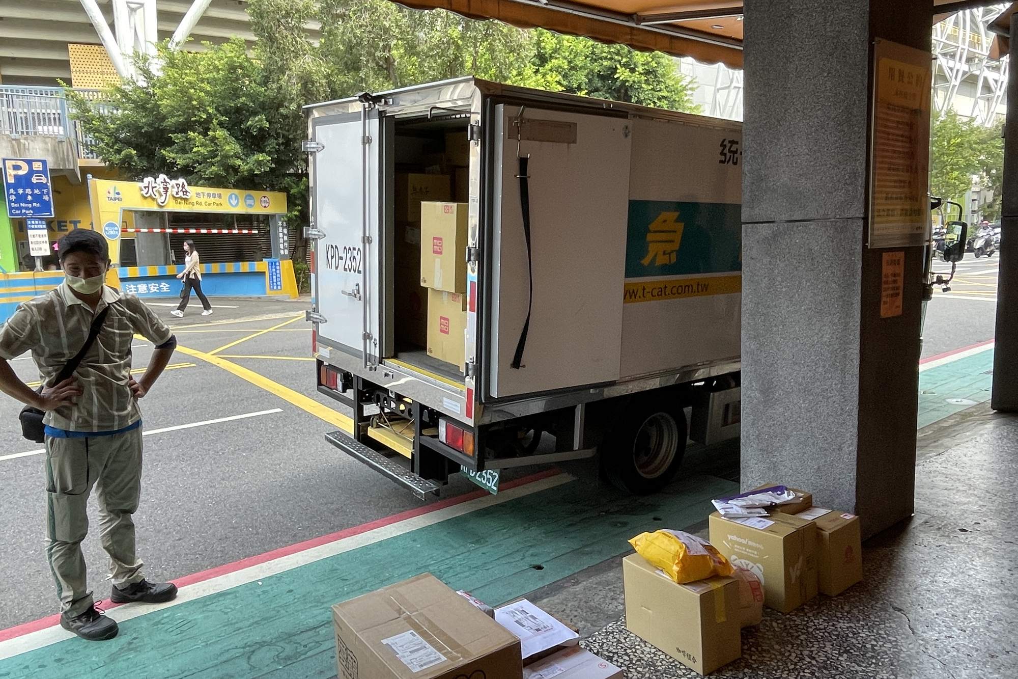 A courier arranges parcels next to a delivery van