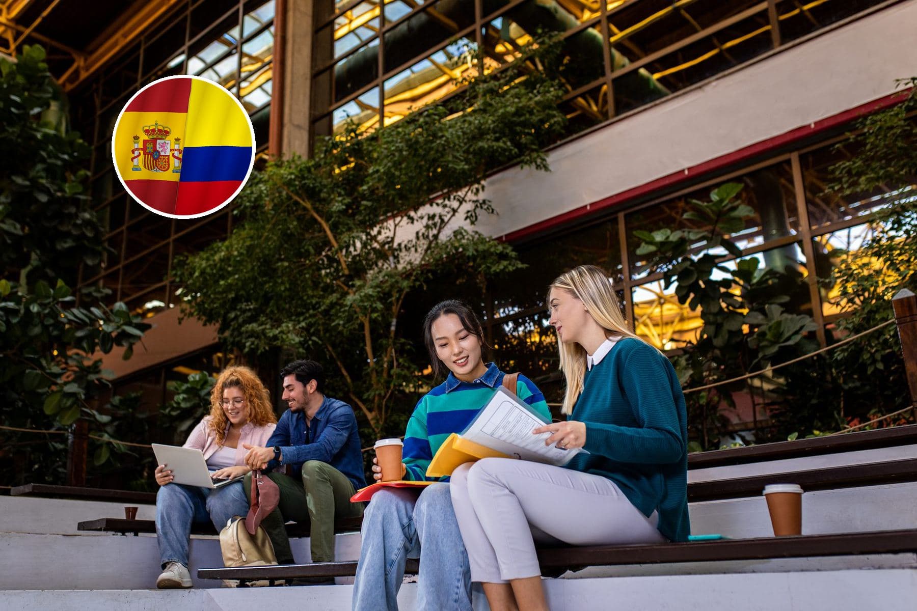 Students sitting on the steps of a university campus with an indoor garden, with laptops, notes and coffees In the corner, the flag of Colombia merged with Spain's.