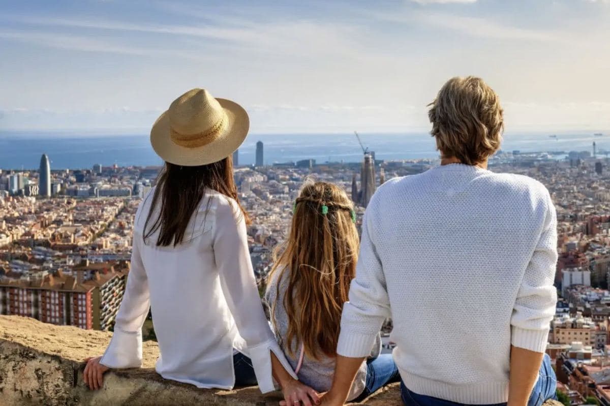 A couple with their daughter, seen from behind, look out over Barcelona from a viewpoint
