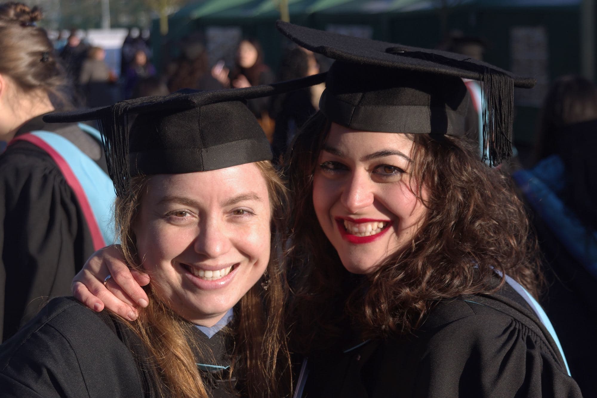 Two graduates in caps and gowns smile on their graduation day