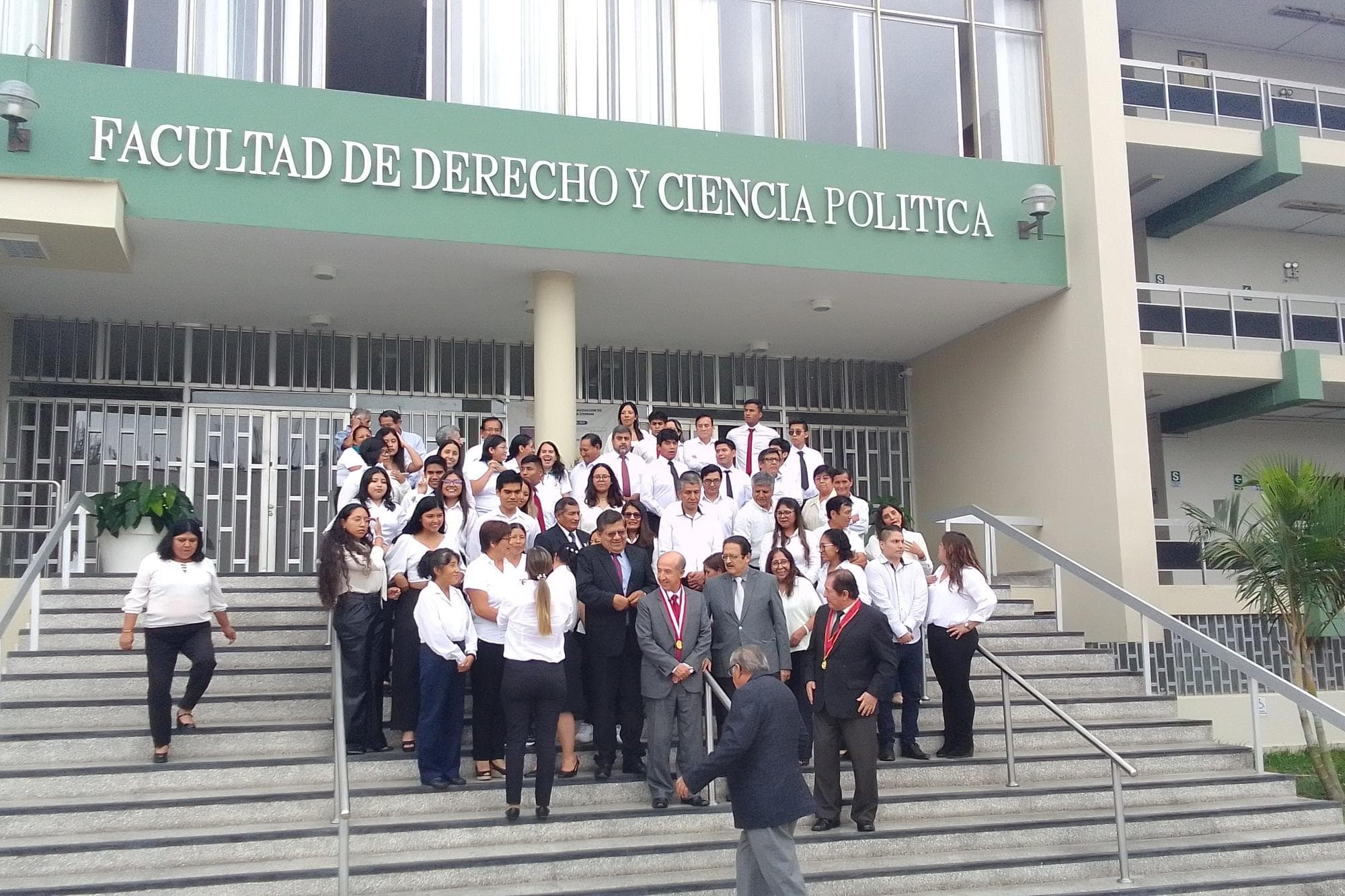 Students and professors pose on the steps of a university faculty in Lima