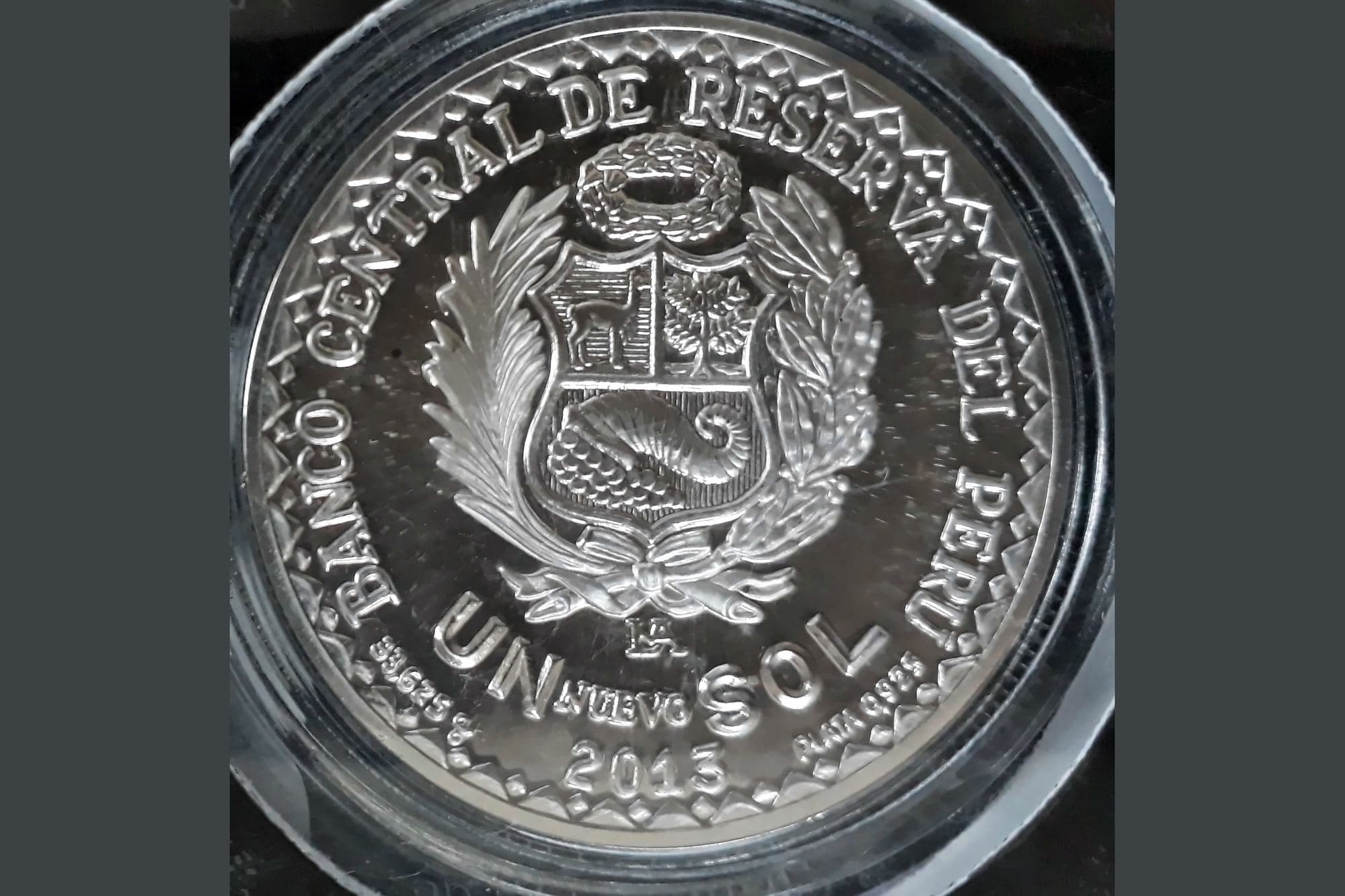 A Peruvian one-sol coin on a dark background