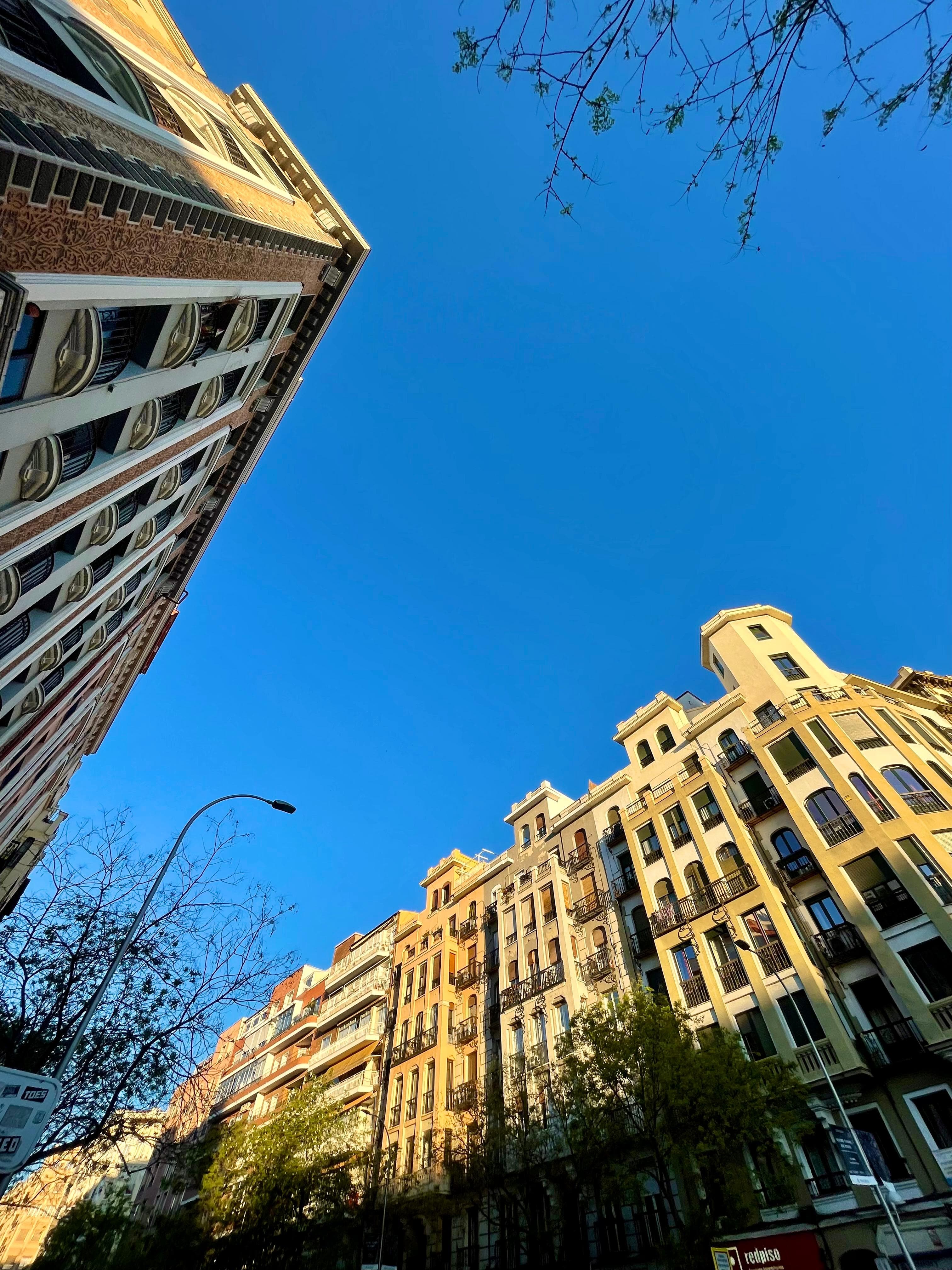 Madrid apartment buildings seen from the pavement, with balconies and a blue sky
